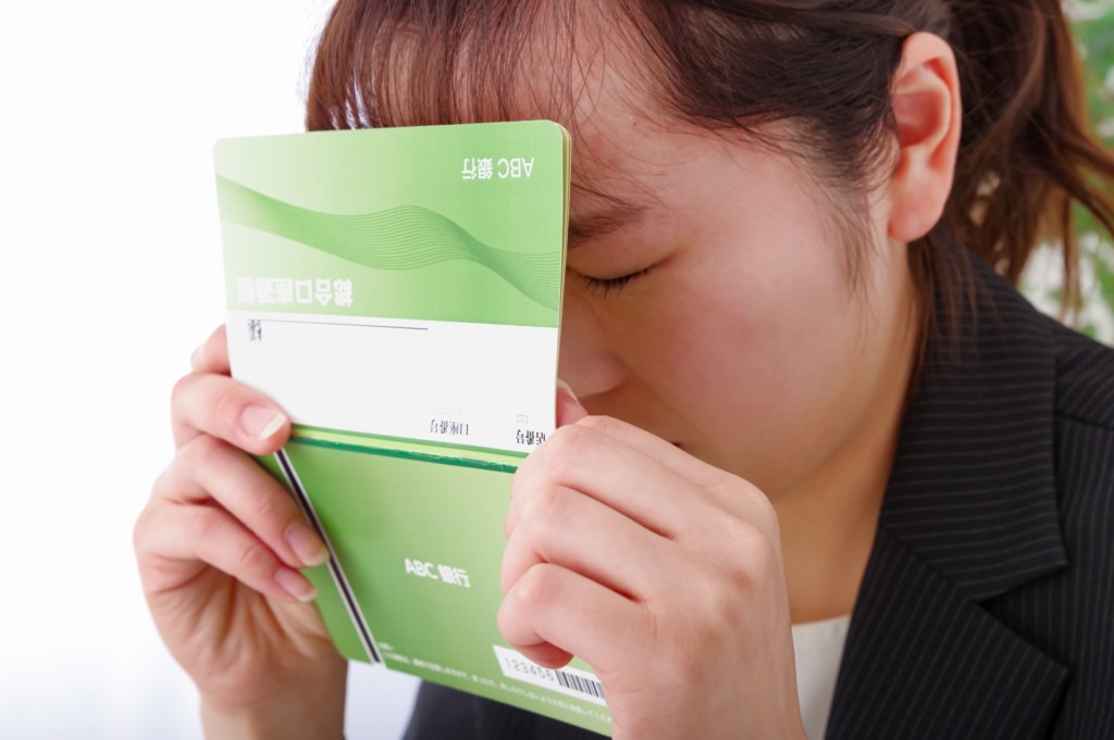 通帳を持って絶望する女性